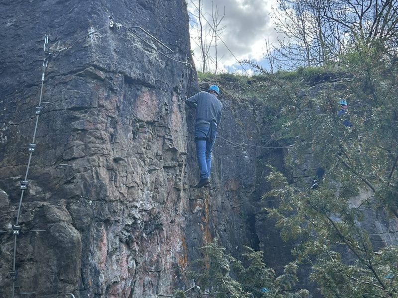 John Robson in a safety gear and harness taking on the Via Ferrata challenge on a rock face in a quarry
