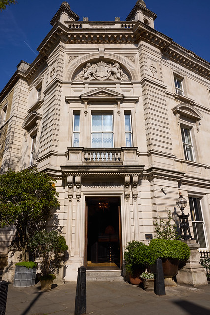 An external view of NoMad London on a sunny day. It's a large, historic stone building with greenery around the front door.