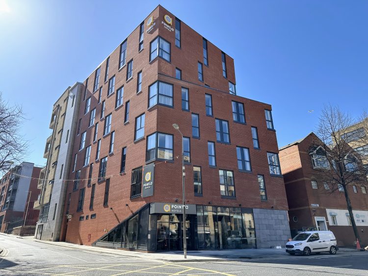 Exterior image of Point a Liberties Hotel. A large red brick building with windows and point a signage above the door