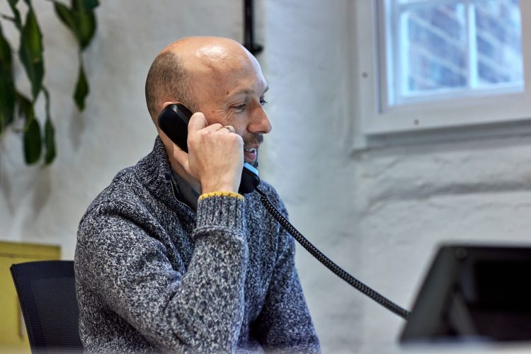 John on the phone in the Morrison Design studio - he's wearing a woolly jumper