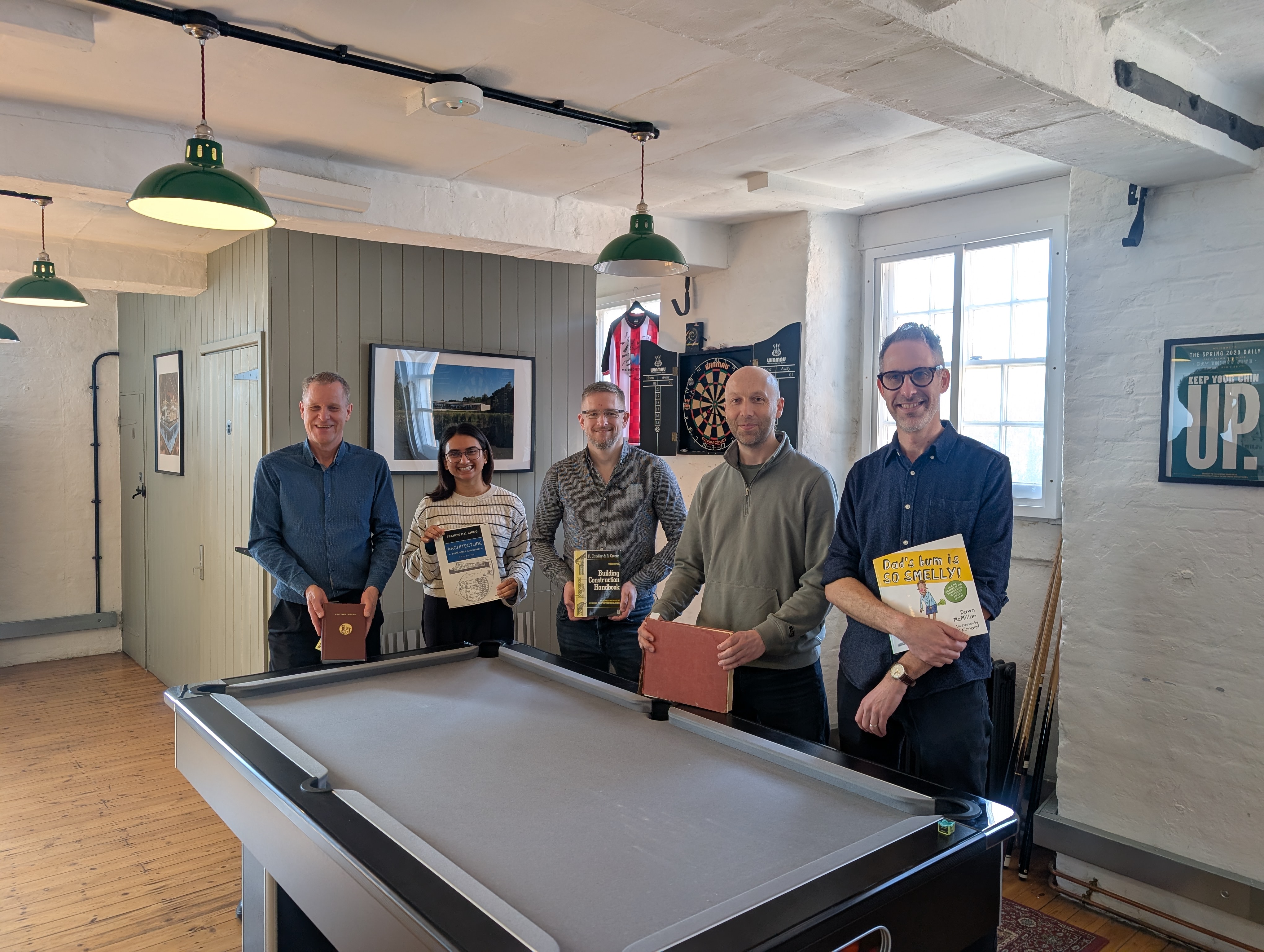 Dale, Nidhi, Dave, John and Nik stood in the Morrison Design office holding their book picks.