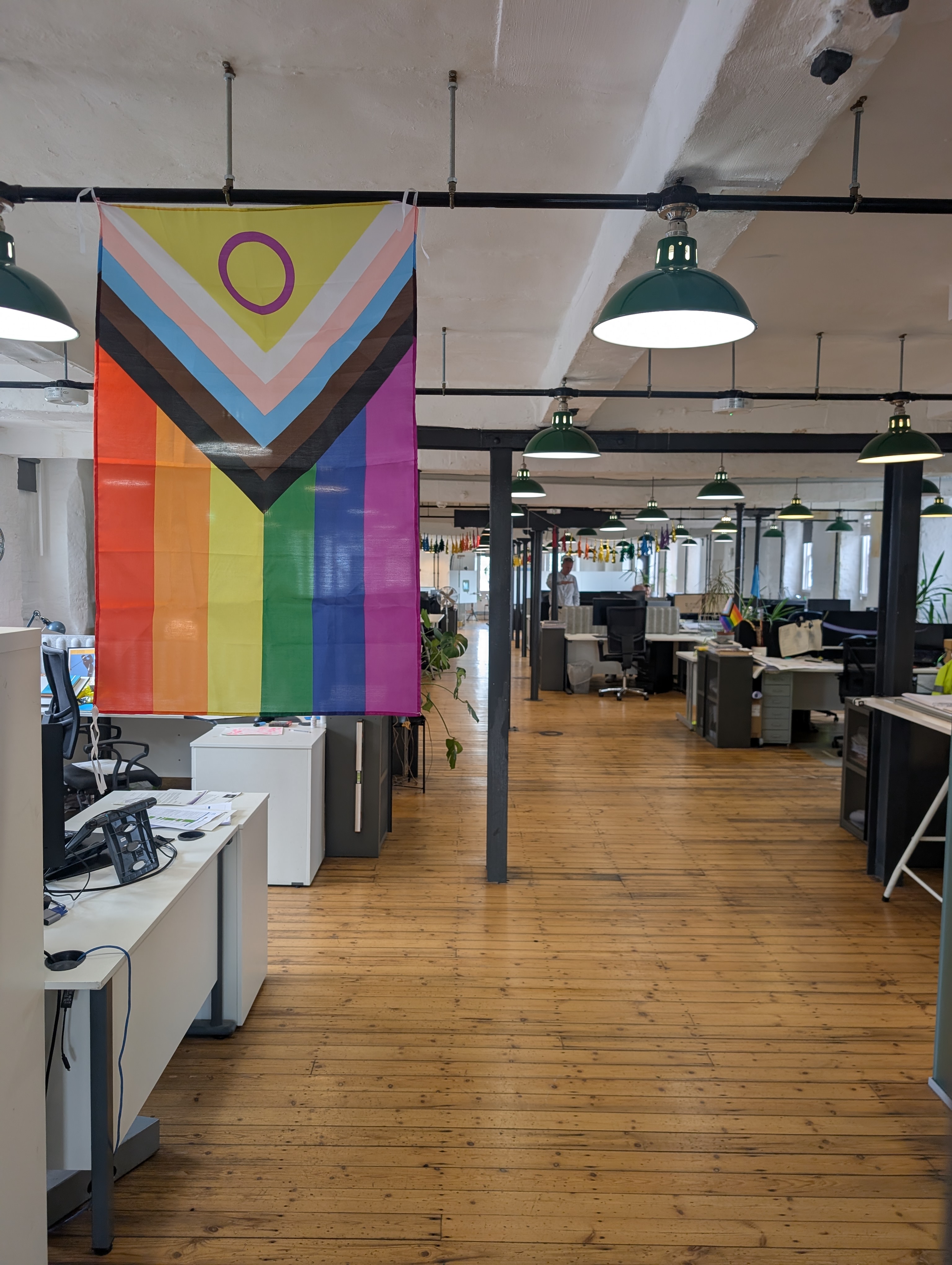 The Pride flag hanging in the studio with colourful decorations in the background.