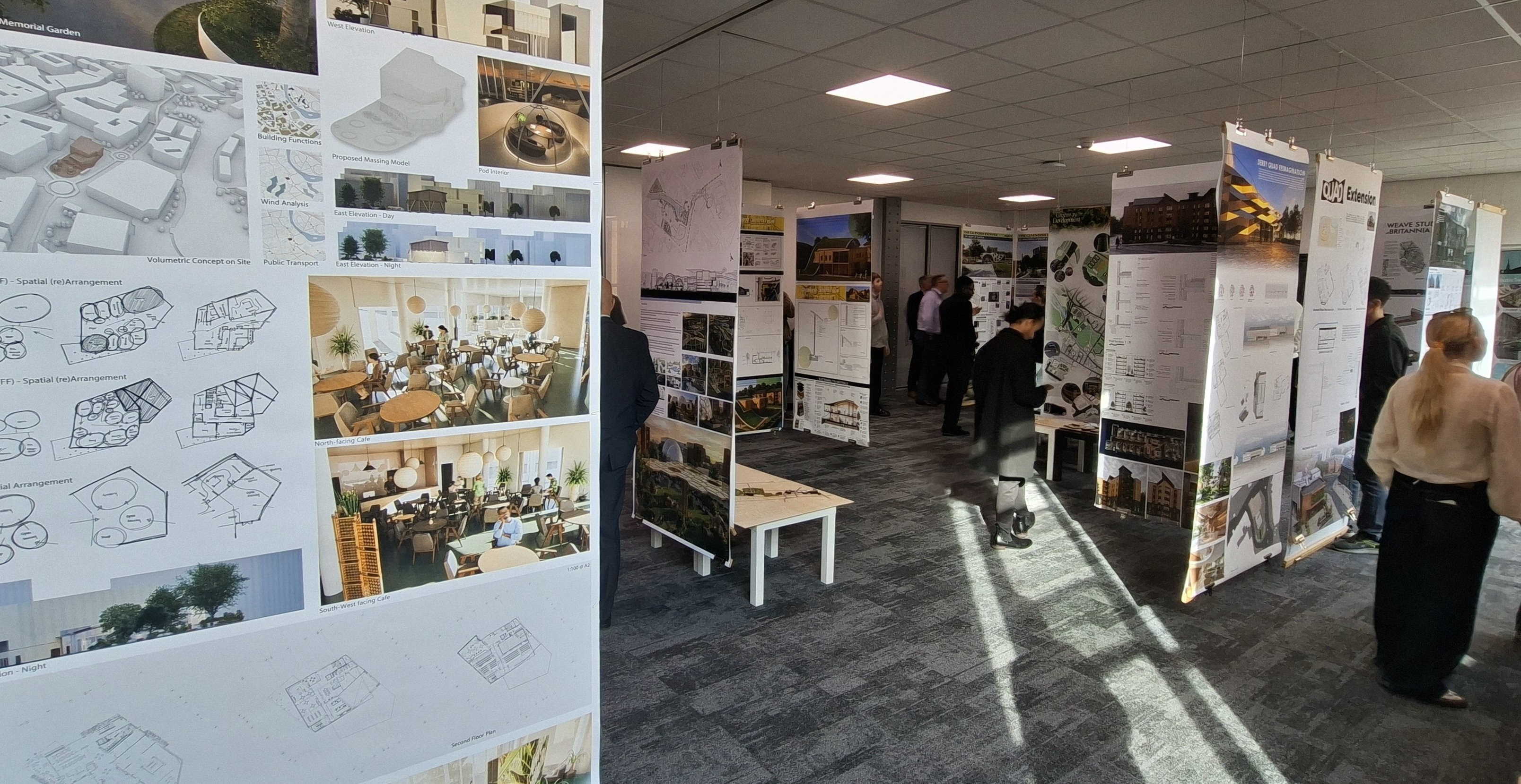 University degree show – lots of tall vertical panels displaying the students work. A few people are looking at the exhibition.