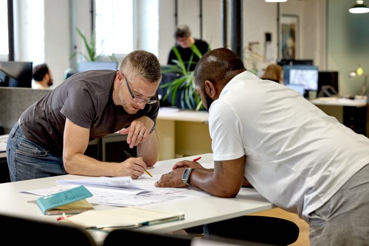 David Gardner leaning over some plans at the drawing table with Sef Lawrence.